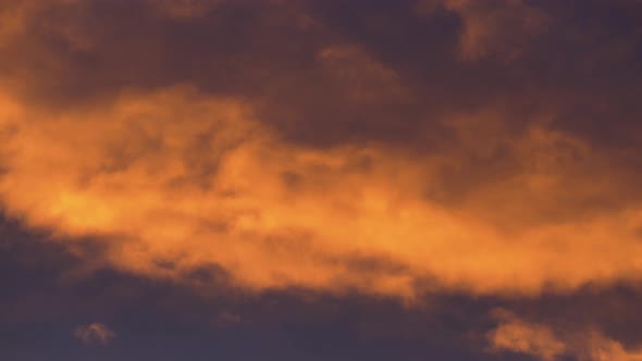 Golden Clouds at Sunset Floating Across Dramatic Violet and Purple Thunderclouds