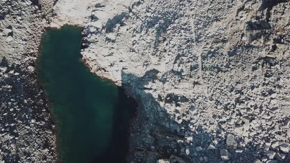 Top aerial view of an alpine lake next to rocky mountains, cabane d'Orny, switzerland, drone alt