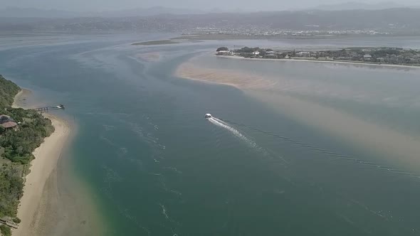 Tour boat stays in deep channel returning to port in Knysna, aerial alt