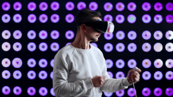 A Man in Virtual Reality Helmet Shoots a Machine Gun in a Computer Game