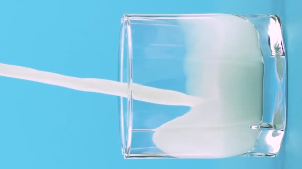 Vertical Video Slow Motion Closeup Shot of Milk Cold Beverage Drink Pooring Into Low Glass with