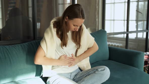 Young Woman is Suffering From Abdominal Pain at Home on the Couch alt