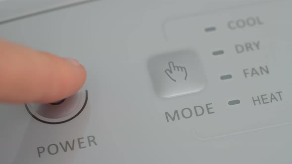 The Person Presses the Start Button with His Finger on a Mobile Air Conditioner to Warm Up the Room
