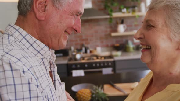 Senior Caucasian couple dancing and smiling in the kitchen alt