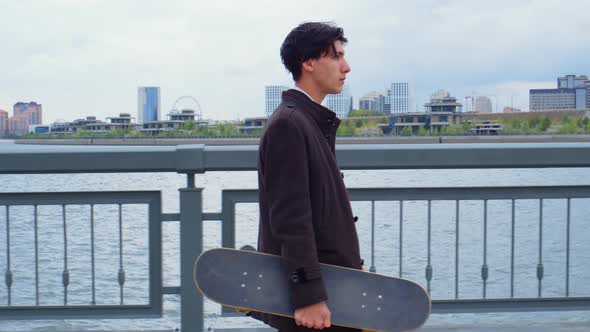 Guy Goes on Embankment with Skateboard