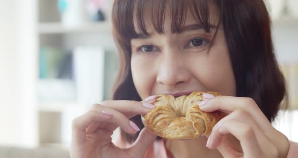 Young woman Biting to eat a big Croissant with delicious