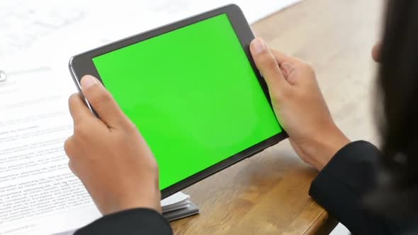 Businesswoman holding empty green screen tablet computer discussing work with colleague