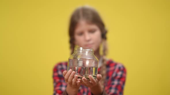Catfish Swimming in Aquarium Bottle with Blurred Teenage Girl at Yellow Background alt