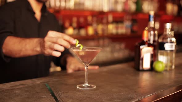 Bartender adding finishing touch to cosmopolitan