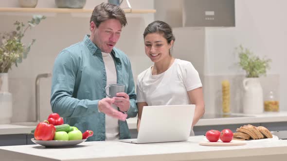 Mixed Race Couple Doing Video Call on Laptop in Kitchen alt