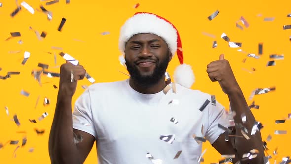 Afro-American Man in Santa Hat Dancing Under Falling Confetti, Carnival Party alt