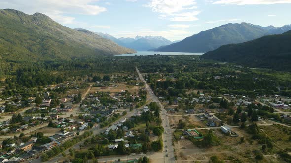 Dolly in flying over Lago Puelo valley with a beautiful woodland, lake and Andean mountains in backg alt