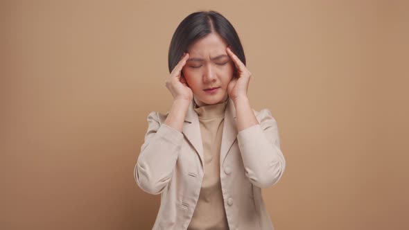 Asian business woman has headache standing isolated over beige background. 4K video