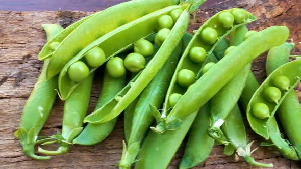 Ripe Young Fresh Green Peas in Pods on a Wooden Board