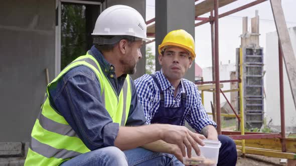 Two Male Engineers Eating at Work alt