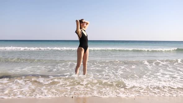 beautiful girl on the beach in a bathing suit by the sea. tanned girl in a black bathing. sea mood