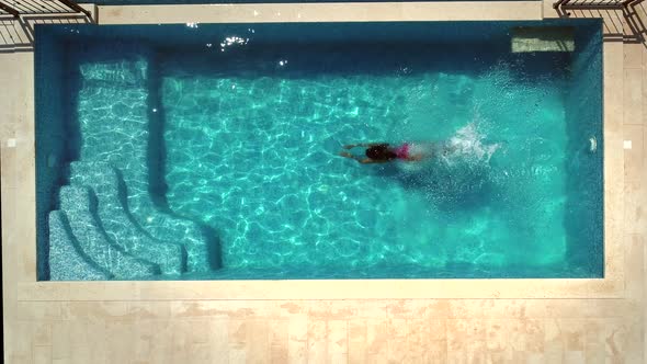 Aerial view of young woman diving into swimming pool. alt