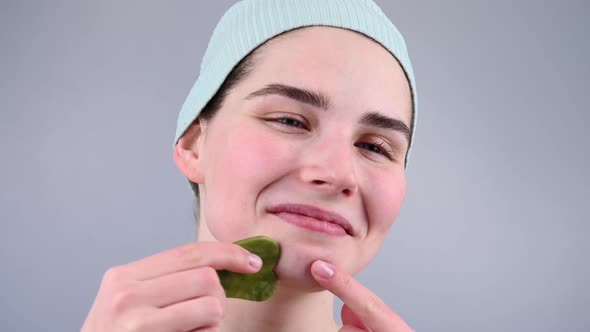 Closeup Portrait of a Young Woman Massaging Her Face with a Gouache Scraper alt
