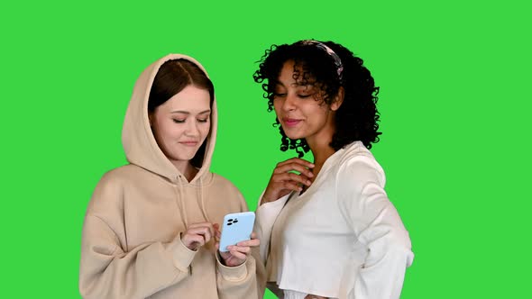 African American and a Caucasian Girl Surfing the Mobile Internet on a Green Screen Chroma Key alt