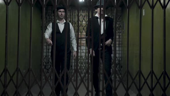 Two Gangsters Men in Formal Suits and Fedora Hat Opening a Metal Forged Gates alt