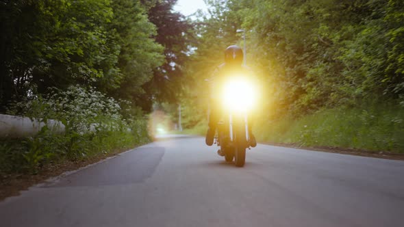 Tracking Shot of a Motorcycle Surrounded By Lush Trees on the Background alt