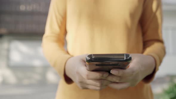 Asian tourist blogger woman using touchscreen technology at smartphone while walking.