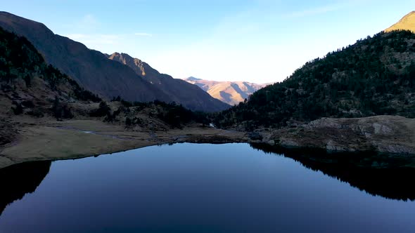 Calm reflecting Lac d'Espingo mountain lake located in Haute-Garonne, Pyrénées, France, Aerial low f alt