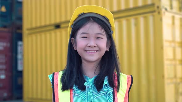 Asian kid girl wearing reflective shirt and hard hat safety, Smiling little girl at container cargo