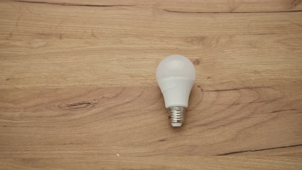 Electricity White Lamp for Lighting Room Lies on Wooden Background alt
