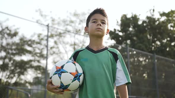 Portrait of Sport Boy with Soccer Ball in the Hand Walking on the Field. alt