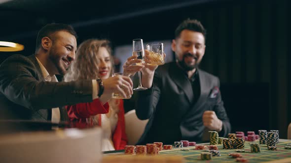 Two Bearded Men and Young Woman are Winning and Rejoice in Victory at the Casino alt