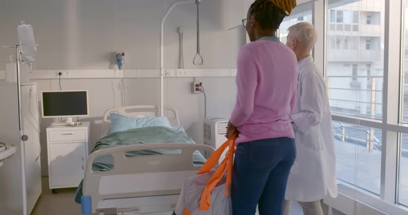 Senior Female Doctor Leading Afroamerican Patient to Hospital Ward alt