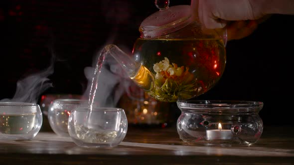 Pouring Fresh Brewed Flower Tea into a Glass Mug. alt