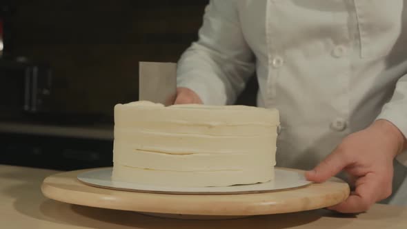 the Man Pastry Chef Rotates the Cake Blank and Evens the Shape with a Special Spatula