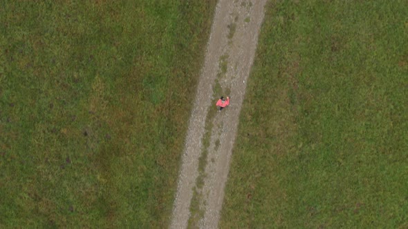 Aerial View, Following Woman Jogging Along Path on Meadow From Above