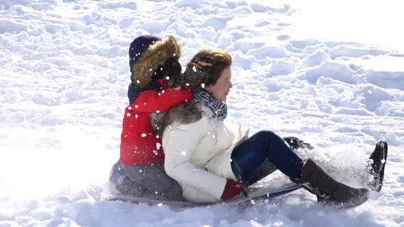 Asian Mother And Her Son  Sliding On Sleds Down Snow Hill In Winter alt