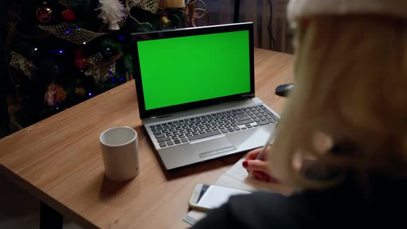 Female person writing and looking at laptop green screen at home indoors at christmas alt