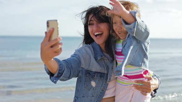 Mother and Daughter Talking Online By Video Call on Cellphone in Summer Sea. Portrait of Smiling