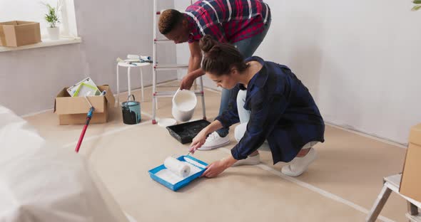 Two Happy Young People in Love are Renovating Their First Purchased Apartment They are Kneeling on alt