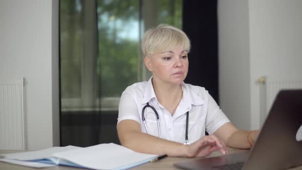 The Blonde Concentrated Women Physician is Checking the Data About Patients