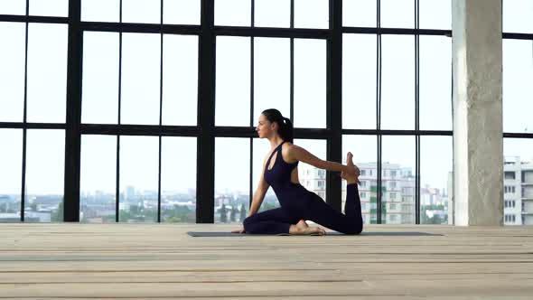 Young athletic girl doing sports in modern studio with big windows alt