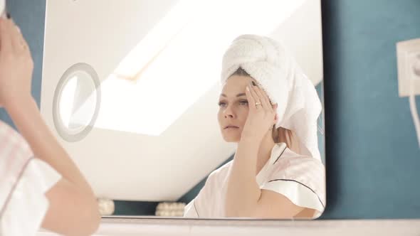 Brunette Girl in Coat and Towel and Looking at Mirror