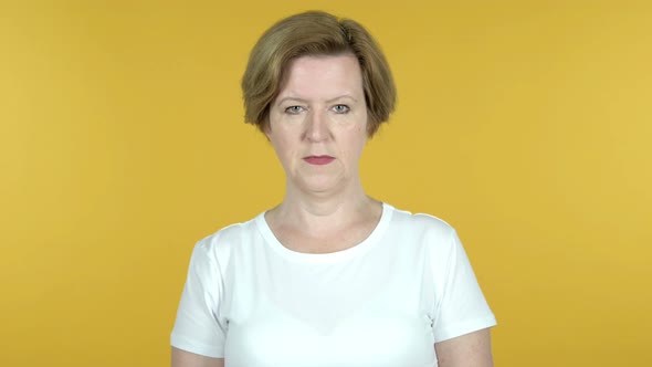 Old Woman Looking at Camera Isolated on Yellow Background alt