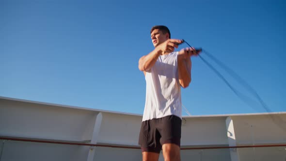 Athletic Young Man in White Tshirt Jumps on Rope Outdoor