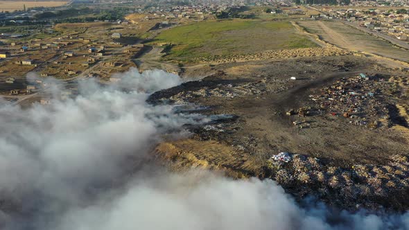Aerial view of burning garbage pile in trash dump or landfill alt