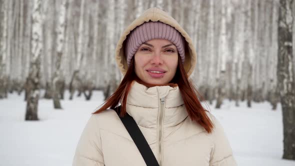 Portrait of a Young Girl in a Beige Jacket That Stands in the Birch Snow Forest