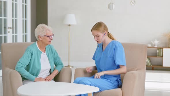 Senior woman patient undergoes examining with stethoscope and doctor listens to heartbeat alt