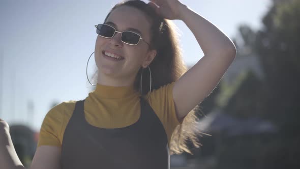 Close-up of Charming Coquette Caucasian Young Woman in Sunglasses Posing in Sunlight Outdoors alt