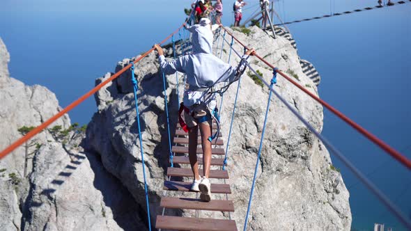 Girls Crossing the Chasm on the Rope Bridge