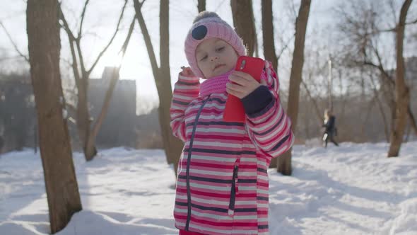 Child Girl Blogger Making Video Call on Mobile Phone Selfie Photo for Social Networksin Winter Park alt